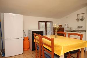 a kitchen with a table and a white refrigerator at Apartments with a parking space Starigrad, Paklenica - 6647 in Starigrad