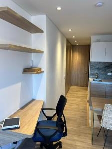 a room with a desk and a chair and a kitchen at Espectacular apartamento en Chapinero in Bogotá