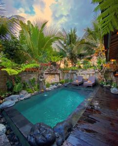 a swimming pool in a garden with palm trees at Honeymoon Green Villa in Ubud