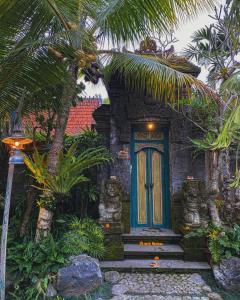 een klein huis met een blauwe deur en palmbomen bij Honeymoon Green Villa in Ubud