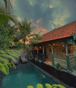 a villa with a swimming pool in front of a house at Honeymoon Green Villa in Ubud