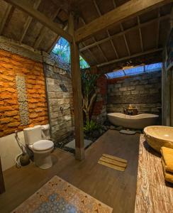 a bathroom with a tub and a toilet and a sink at Honeymoon Green Villa in Ubud