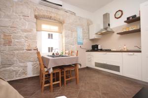 a kitchen with a table and chairs and a stone wall at Apartments by the sea Funtana, Porec - 6905 in Funtana