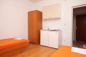 een keuken met een bed, een koelkast en kasten bij Apartments and rooms with parking space Podgora, Makarska - 6790 in Podgora