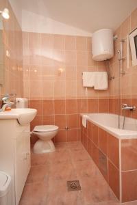 a bathroom with a tub and a toilet and a sink at Apartments by the sea Podgora, Makarska - 6673 in Podgora