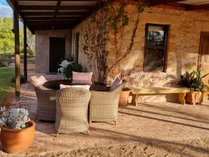 un patio con sillas de mimbre, mesa y banco en Sandalmere Cottage en Cadell