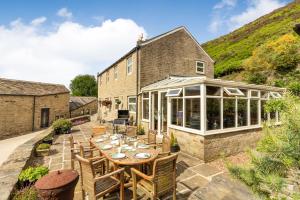 a patio with a table and chairs and a house at Long Ing Farm in Holmfirth