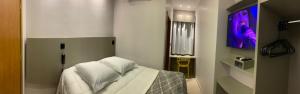 1 dormitorio con 1 cama blanca y TV en Hotel Villa Inácia, en Vacaria