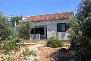 a small stone house with a porch and trees at Secluded fisherman's cottage Cove Suha Punta, Kornati - 8168 in Pinizelić