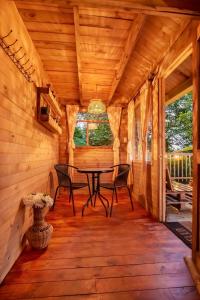 a wooden porch with a table and chairs in a cabin at Entremonte Cabañas in La Vega