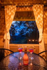 dois copos de vinho sentados numa mesa em frente a uma janela em Entremonte Cabañas em La Vega