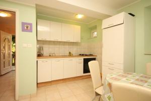 a kitchen with white cabinets and a table and a dining room at Holiday house Lastovo - 8289 in Lastovo