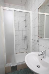 La salle de bains blanche est pourvue d'une douche et d'un lavabo. dans l'établissement Apartments by the sea Bilo, Primosten - 8364, à Primošten