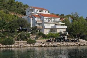 a large white building on a hill next to the water at Apartments by the sea Pasadur, Lastovo - 8351 in Ubli
