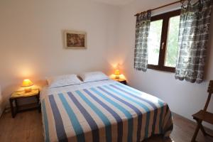sypialnia z łóżkiem z paskowym kocem i 2 lampami w obiekcie Apartment Zaglav 8170b w mieście Sali