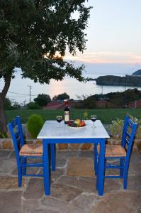 a blue table with two chairs and a bottle of wine at Sunset Hotel in Agios Ioannis Kaspaka