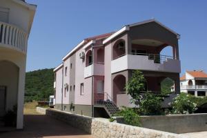 ein rosafarbenes Gebäude mit einer Steinmauer neben einem Gebäude in der Unterkunft Apartments by the sea Pasman - 8217 in Pašman