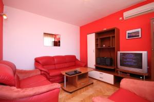 a red living room with a red couch and a tv at Seaside holiday house Kali, Ugljan - 8429 in Kali