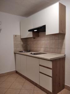 eine Küche mit weißen Schränken und einem Waschbecken in der Unterkunft Apartments with a parking space Ugljan - 8527 in Ugljan