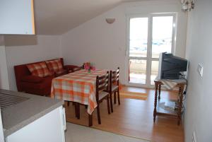 a living room with a table and a kitchen with a television at Apartment Kukljica 8478a in Kukljica
