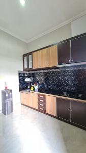a large kitchen with wooden cabinets and a tile floor at Oemah Wisata RinginSari -Full House, 5 Bed Rooms- in Kalasan