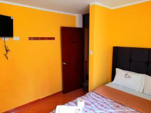 a bedroom with yellow walls and a bed and a red door at Hospedaje Las Lilas in Huancayo