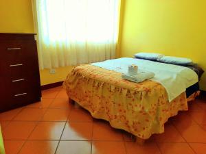Un dormitorio con una cama con una mesa con una vela. en Hospedaje Las Lilas, en Huancayo