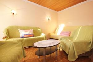 salon z 2 zielonymi krzesłami i stołem w obiekcie Apartments by the sea Kastel Stafilic, Kastela - 8621 w mieście Kaštela