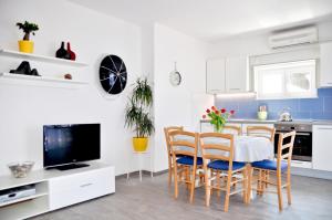 Apartments by the sea Razanj, Rogoznica - 8365 في روغوزنيكا: مطبخ مع طاولة وكراسي وتلفزيون