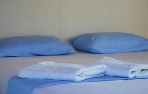 two beds with blue pillows and towels on them at Sunset Hotel in Agios Ioannis Kaspaka