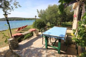 a table and chairs on a patio next to the water at Seaside house for families with children Cove Soline, Pasman - 8482 in Kraj