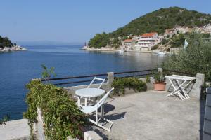 a table and chairs on a balcony overlooking a body of water at Studio Zaklopatica 8393a in Lastovo