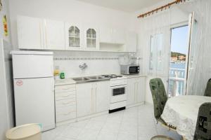 Biała kuchnia ze zlewem i lodówką w obiekcie Apartments by the sea Kukljica, Ugljan - 8229 w mieście Kukljica