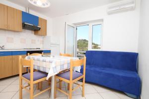 a kitchen with a table and chairs and a blue couch at Apartment Tkon 8377a in Tkon