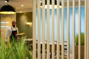 un homme traversant une pièce avec une clôture dans l'établissement Hotel Paka, à Velenje