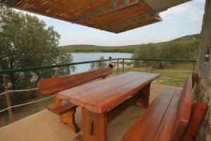 a wooden bench on a balcony with a view of a lake at Seaside house for families with children Cove Sveti Ante, Pasman - 8499 in Kraj +16 photos