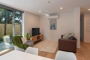 a living room with two chairs and a tv at Malthouse Lane City Apartment 2 in Nelson