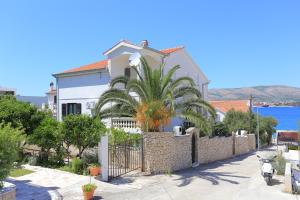 uma casa com uma palmeira em frente a uma parede em Apartments by the sea Okrug Gornji, Ciovo - 8625 em Trogir