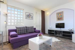 uma sala de estar com um sofá roxo e uma televisão em Apartments by the sea Okrug Gornji, Ciovo - 8625 em Trogir