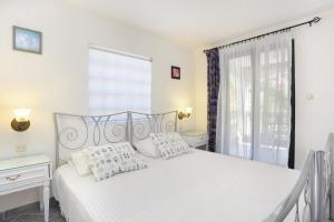 um quarto com uma cama branca e uma janela em Apartments by the sea Okrug Gornji, Ciovo - 8625 em Trogir