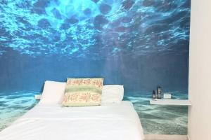 a bedroom with a bed in front of a painting of the ocean at Loft 15 comodo y confortable , cerca del centro de gobierno , galerias mall, consulado , CAS , Pepsi in Hermosillo
