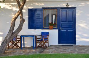a house with a blue door and two chairs and a table at Sunset Hotel in Agios Ioannis Kaspaka