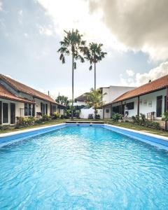 a swimming pool in front of some houses and palm trees at Nami Surf Stay in Canggu
