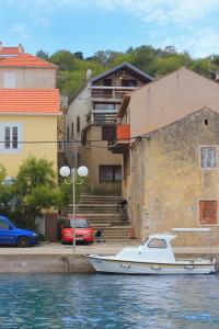 a white boat in the water next to a building at Apartments by the sea Sali, Dugi otok - 8193 in Sali