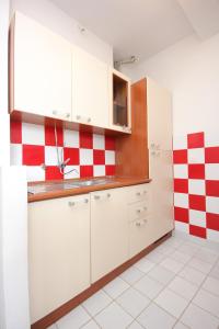 a kitchen with white cabinets and red and white checkered wall at Apartments by the sea Sali, Dugi otok - 8193 in Sali