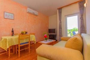 a living room with a table and a yellow couch at Apartments 4 Palme in Funtana