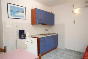 małą kuchnię z niebieskimi szafkami i zlewem w obiekcie Apartments by the sea Kukljica, Ugljan - 8316 w mieście Kukljica