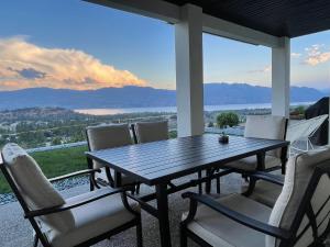 a wooden table and chairs on a porch with a view at Shannon Heights B&B in West Kelowna
