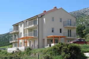 an apartment building on a hill with a car in front at Apartments by the sea Zavala, Hvar - 8637 in Jelsa