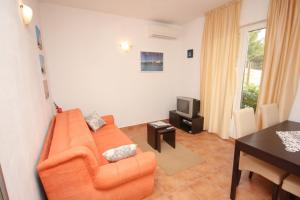 a living room with an orange couch and a television at Apartments by the sea Zavala, Hvar - 8637 in Jelsa